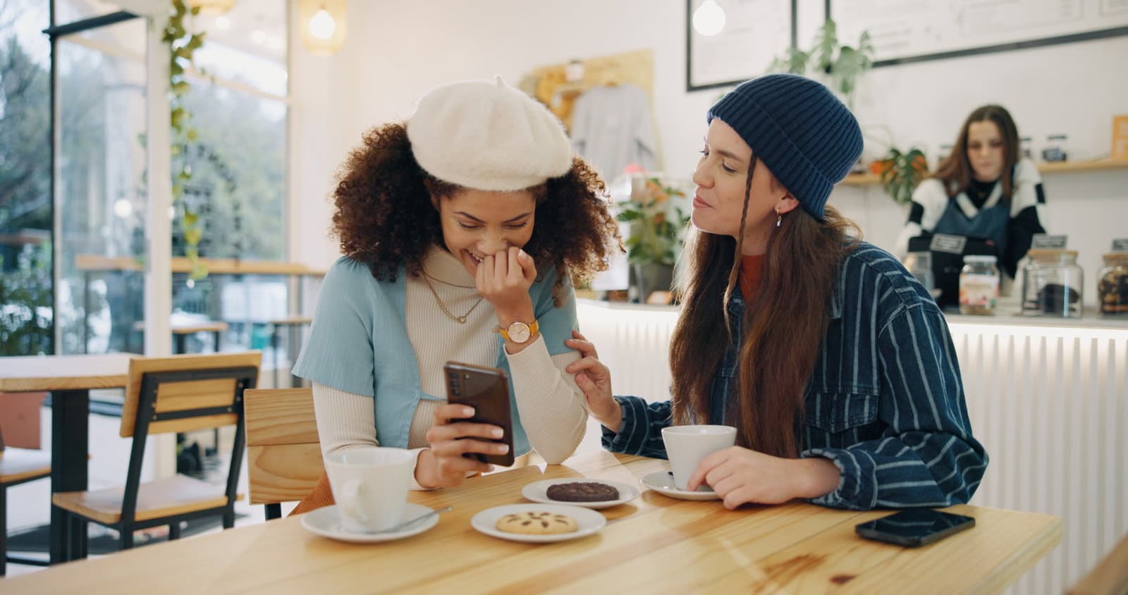 Two friends enjoying coffee while managing finances on their phone